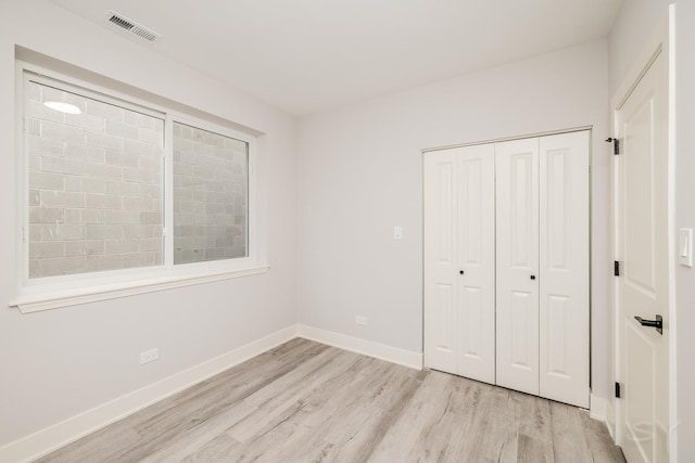 unfurnished bedroom featuring a closet, visible vents, light wood-style flooring, and baseboards