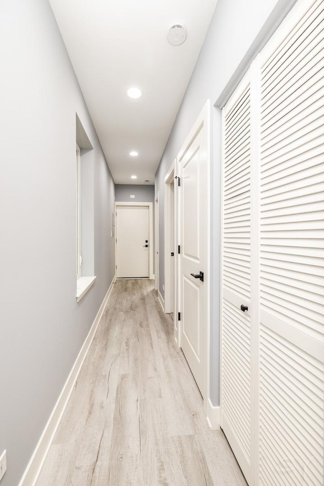 corridor with light wood-style floors and baseboards