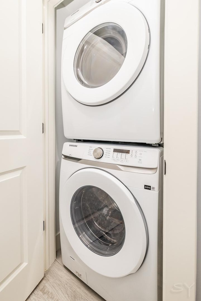 laundry area featuring light wood-type flooring, stacked washer and dryer, and laundry area