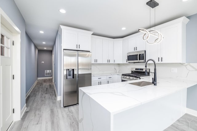 kitchen featuring light stone counters, decorative backsplash, appliances with stainless steel finishes, and a peninsula