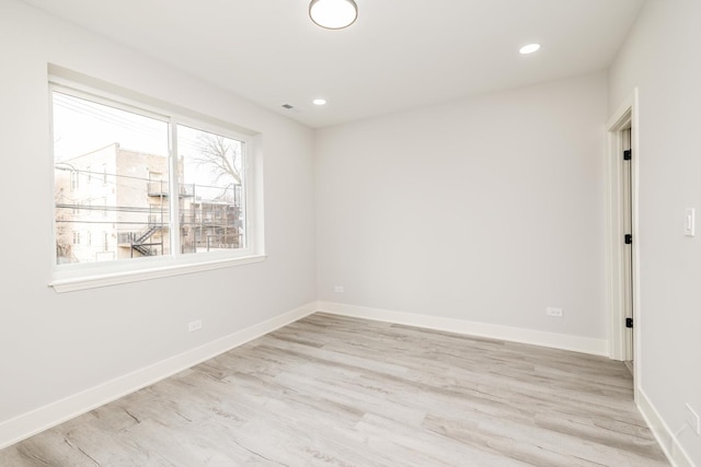 spare room featuring light wood finished floors, recessed lighting, and baseboards