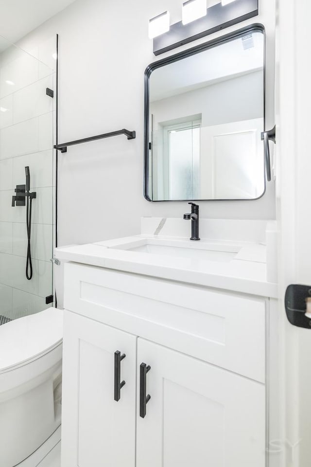 full bathroom featuring tiled shower, toilet, and vanity