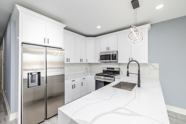 kitchen featuring backsplash, light stone counters, white cabinets, stainless steel appliances, and a sink