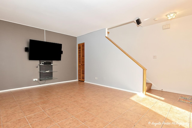 unfurnished living room featuring light tile patterned floors, stairway, and baseboards