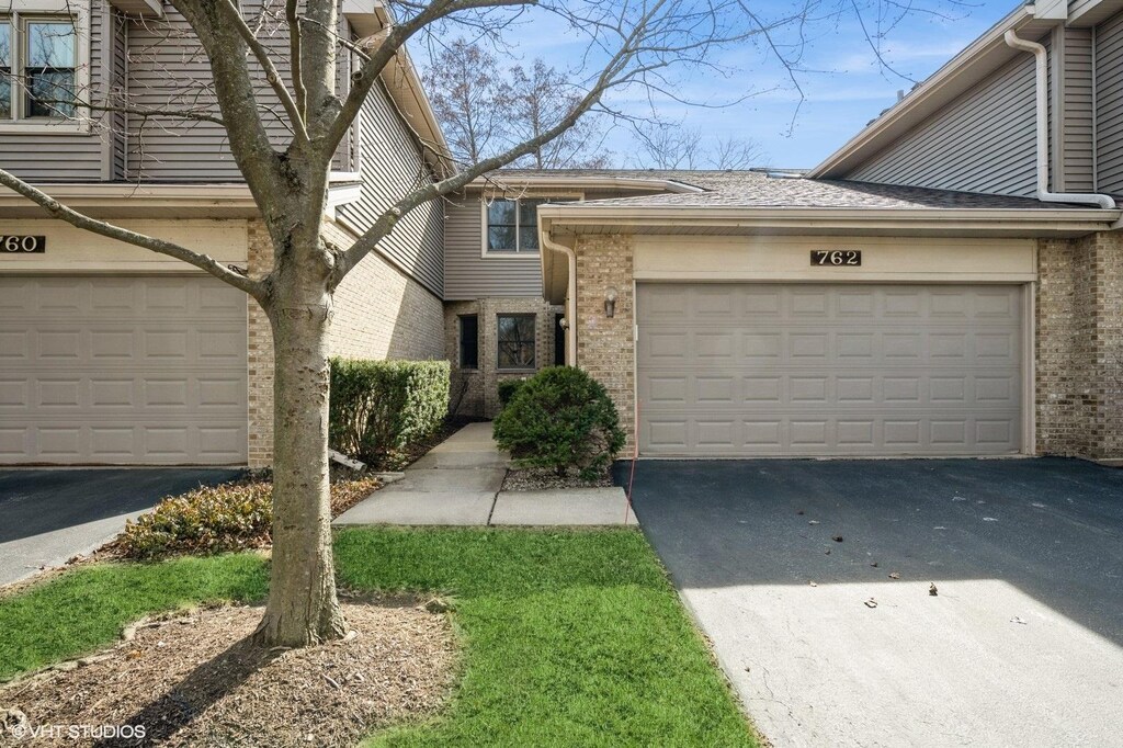 townhome / multi-family property featuring brick siding, driveway, and an attached garage