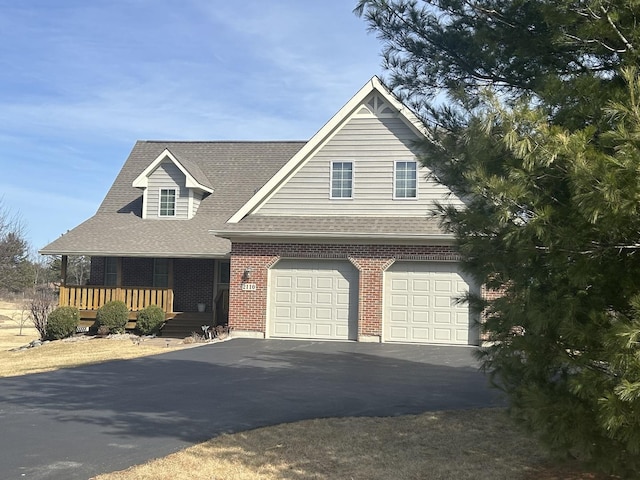 view of front of home with brick siding, aphalt driveway, roof with shingles, covered porch, and a garage