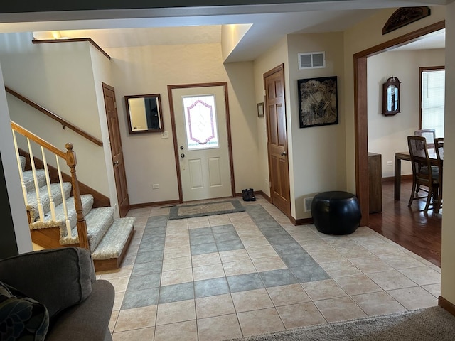 foyer entrance with stairway, light tile patterned flooring, baseboards, and visible vents