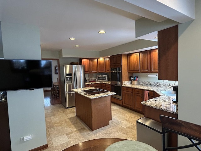 kitchen featuring a center island, recessed lighting, appliances with stainless steel finishes, a toaster, and light stone countertops