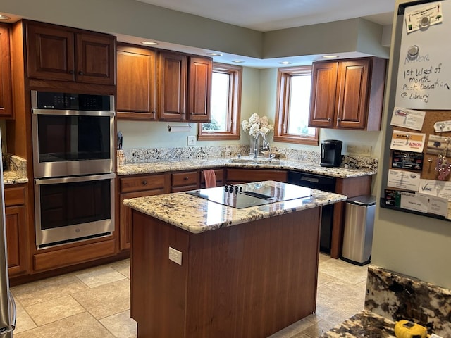 kitchen featuring a sink, light stone counters, a center island, double oven, and black electric cooktop