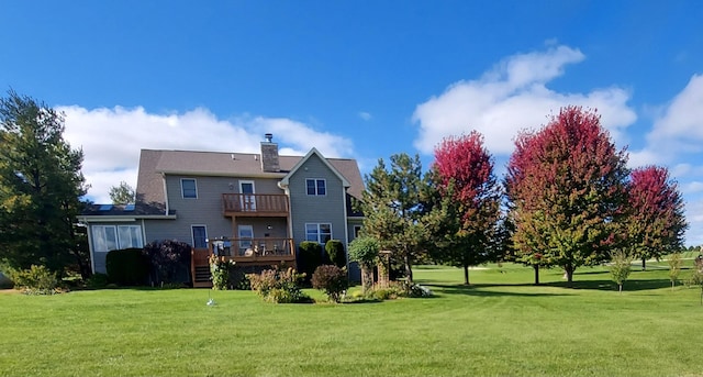 rear view of property with a wooden deck, a balcony, a lawn, and a chimney