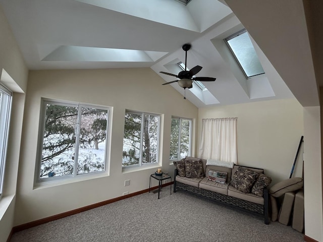 living room featuring baseboards, lofted ceiling with skylight, a ceiling fan, and carpet flooring