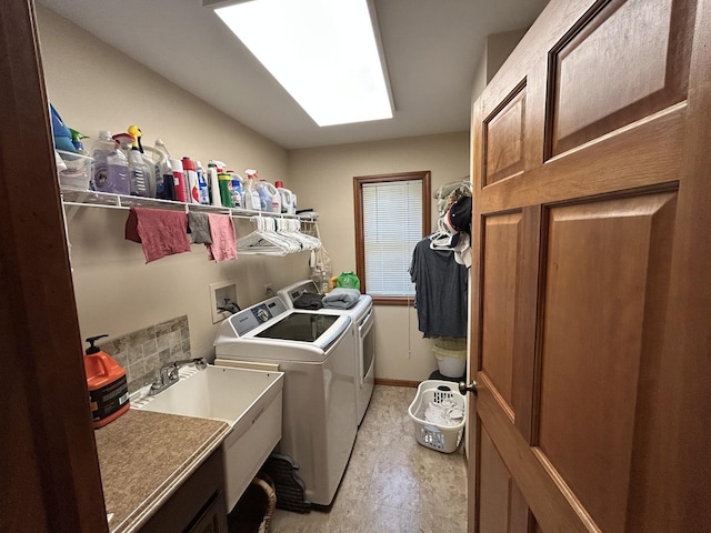 washroom with a sink, washing machine and dryer, a skylight, baseboards, and laundry area