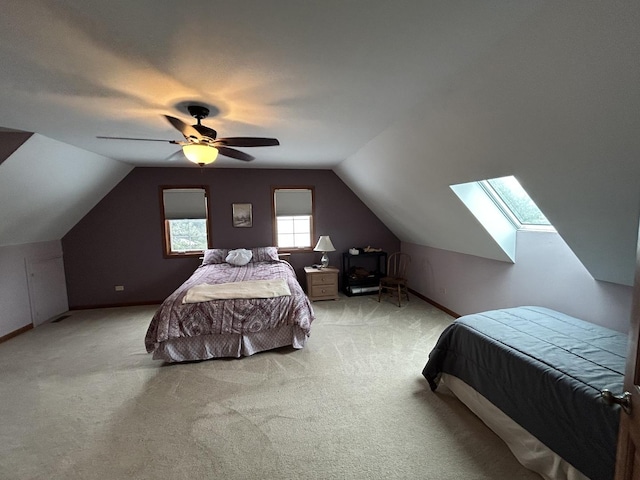 bedroom with lofted ceiling with skylight, light colored carpet, and ceiling fan