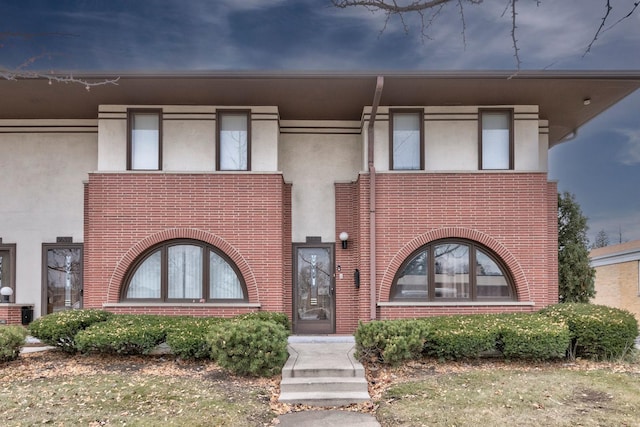 view of front of property featuring brick siding and stucco siding