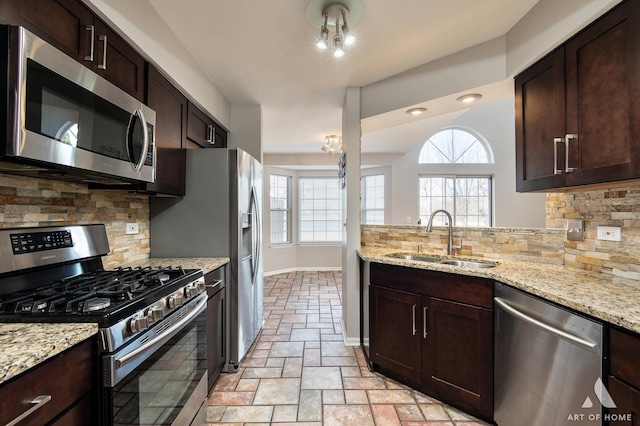 kitchen featuring dark brown cabinets, appliances with stainless steel finishes, baseboards, and a sink