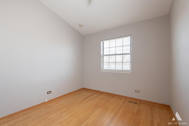 spare room featuring visible vents, baseboards, vaulted ceiling, and light wood finished floors