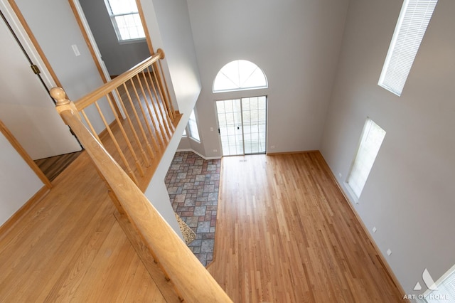 foyer entrance featuring baseboards, a high ceiling, and wood finished floors