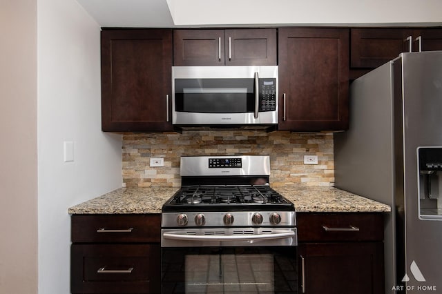 kitchen featuring backsplash, light stone countertops, dark brown cabinetry, and appliances with stainless steel finishes