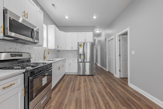 kitchen with visible vents, backsplash, stainless steel appliances, white cabinetry, and a sink