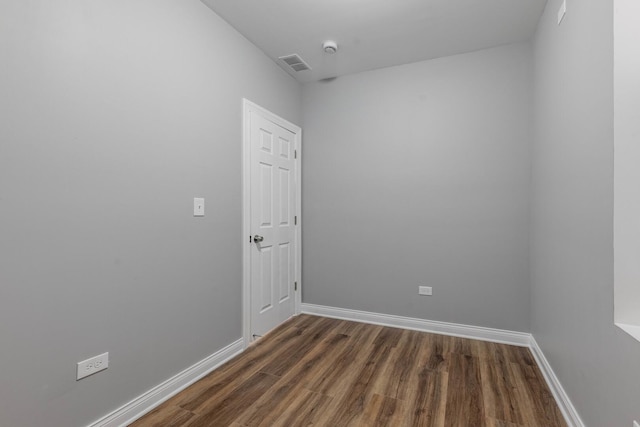 empty room featuring baseboards, visible vents, and dark wood-style flooring