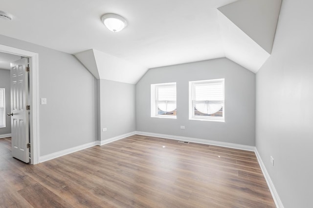 additional living space featuring baseboards, lofted ceiling, visible vents, and wood finished floors