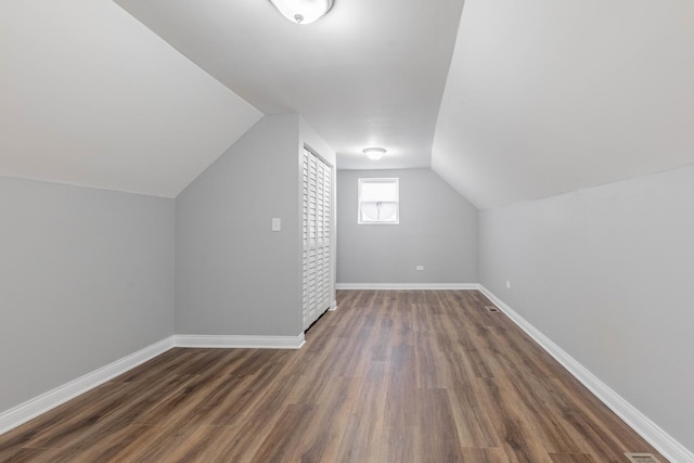 bonus room featuring lofted ceiling, dark wood-type flooring, and baseboards