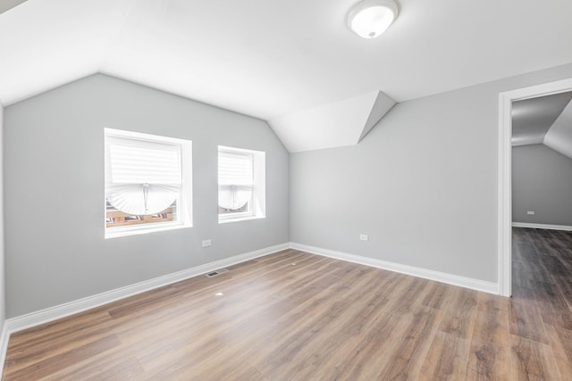 additional living space with visible vents, baseboards, lofted ceiling, and wood finished floors