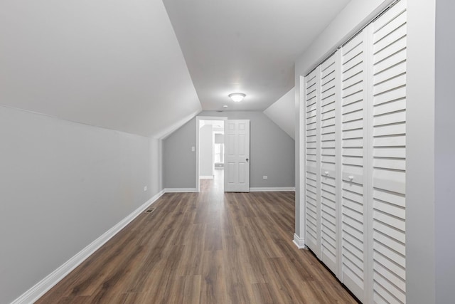 additional living space featuring lofted ceiling, baseboards, and dark wood-style flooring