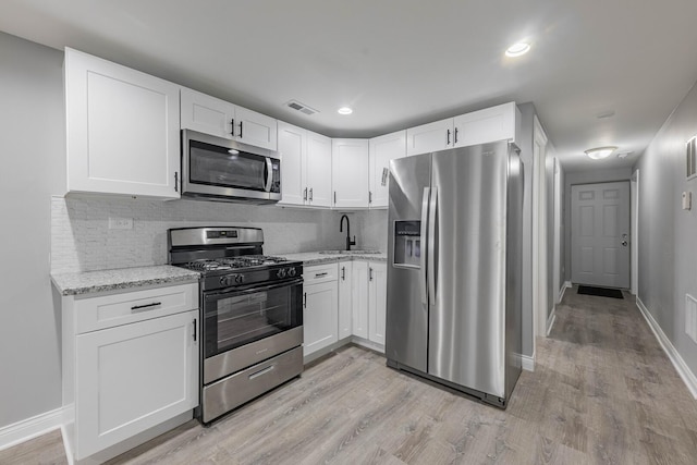 kitchen with light stone counters, visible vents, appliances with stainless steel finishes, and a sink