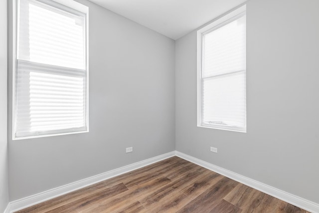 spare room with baseboards and wood finished floors