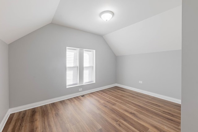 additional living space featuring visible vents, baseboards, lofted ceiling, and wood finished floors