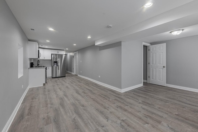 unfurnished living room with light wood finished floors, visible vents, and baseboards