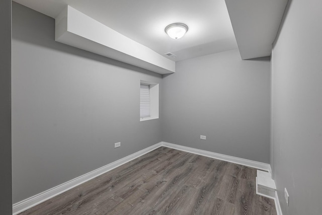 empty room featuring visible vents, baseboards, and dark wood-type flooring