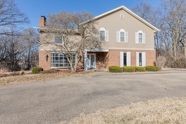 view of front of home featuring brick siding and a chimney