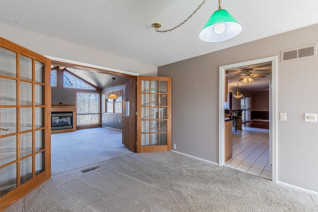 empty room with visible vents, carpet flooring, a textured ceiling, and a glass covered fireplace