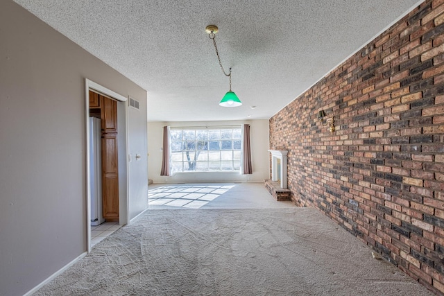 hall with light colored carpet, visible vents, brick wall, and a textured ceiling