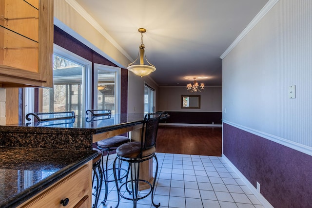 kitchen featuring tile patterned flooring, a wainscoted wall, a chandelier, and ornamental molding