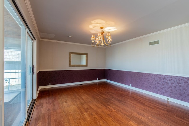 empty room with wood finished floors, baseboards, visible vents, ornamental molding, and a notable chandelier