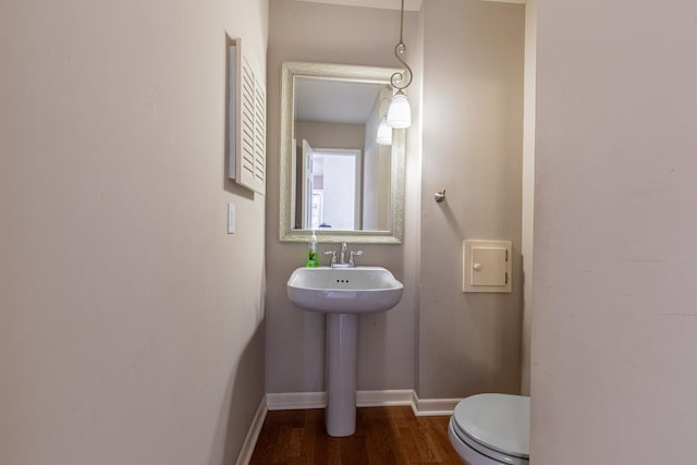 bathroom featuring a sink, toilet, baseboards, and wood finished floors