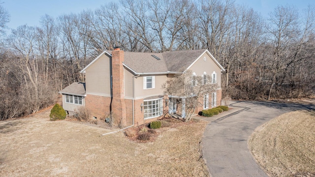 view of front of property featuring a front yard, a shingled roof, a chimney, aphalt driveway, and central air condition unit