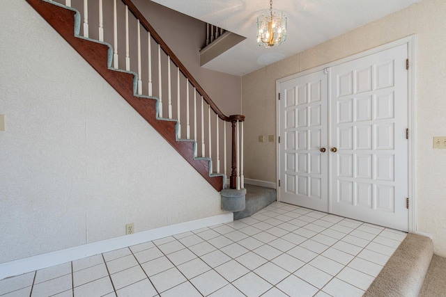 foyer with tile patterned floors, stairway, and an inviting chandelier