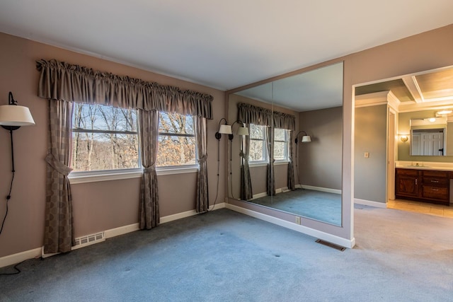 unfurnished room featuring a sink, visible vents, baseboards, and light colored carpet