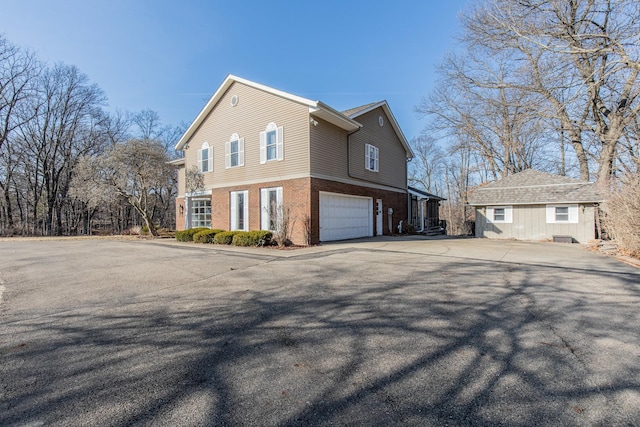 view of side of home with brick siding, concrete driveway, and an attached garage