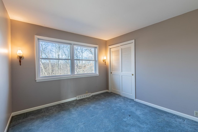 unfurnished bedroom with a closet, visible vents, baseboards, and carpet floors