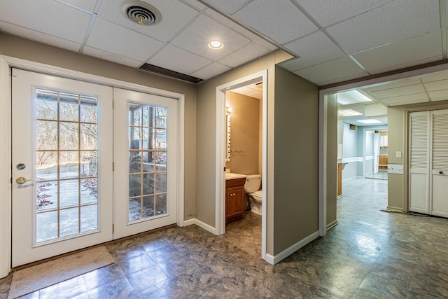 doorway with tile patterned floors, a paneled ceiling, baseboards, and visible vents