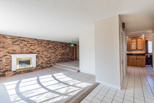 unfurnished living room with light tile patterned floors, brick wall, a fireplace, and a textured ceiling