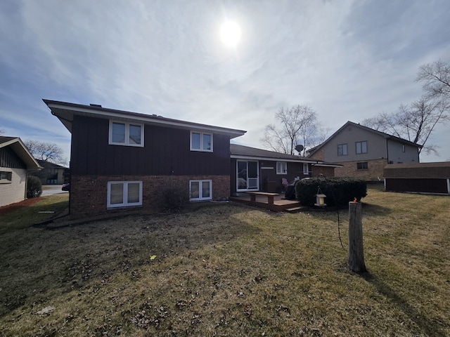 rear view of property featuring a lawn and brick siding