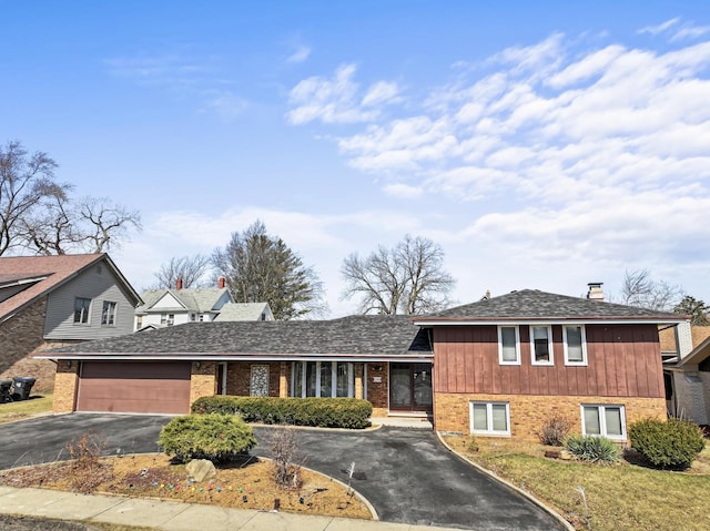 tri-level home featuring brick siding, driveway, and a garage