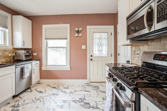 kitchen featuring a wealth of natural light, marble finish floor, appliances with stainless steel finishes, and baseboards