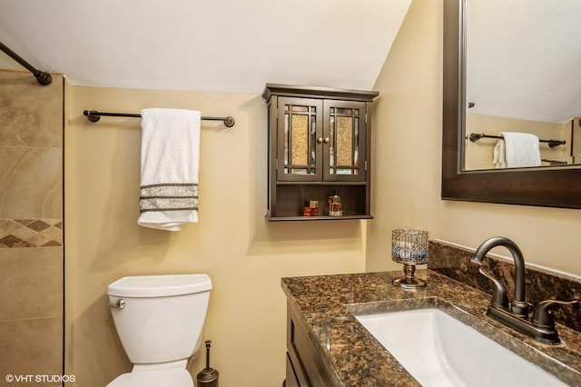 full bath featuring vanity, vaulted ceiling, toilet, and a tile shower